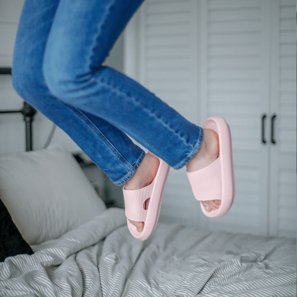 Hoppende dame over seng med rosa Soft Slippers på føttene
